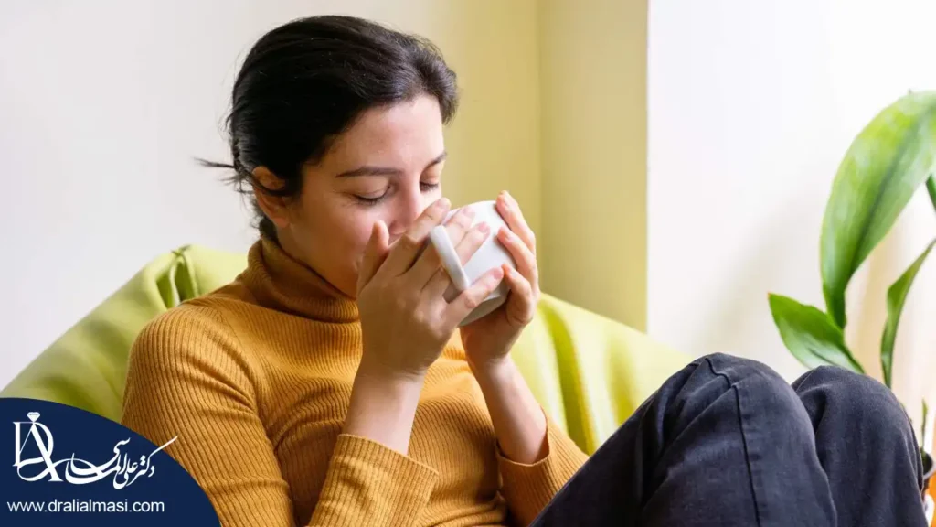 خانمی در حال نوشیدن دمنوش بابونه برای کمک به درمان کم کاری تیروئید